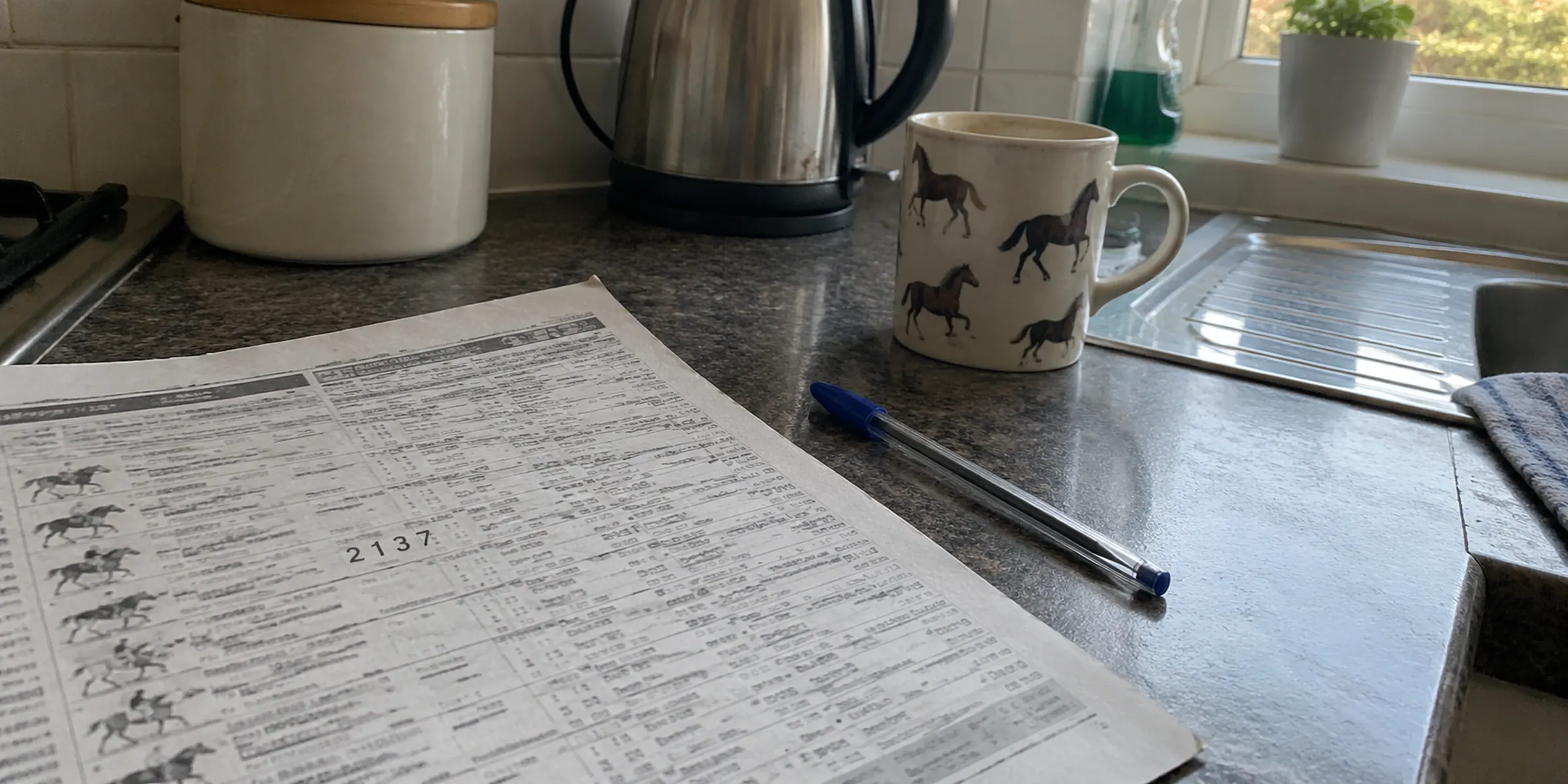 A printed form sheet showing 2 1 3 7 beside a pen on a kitchen counter