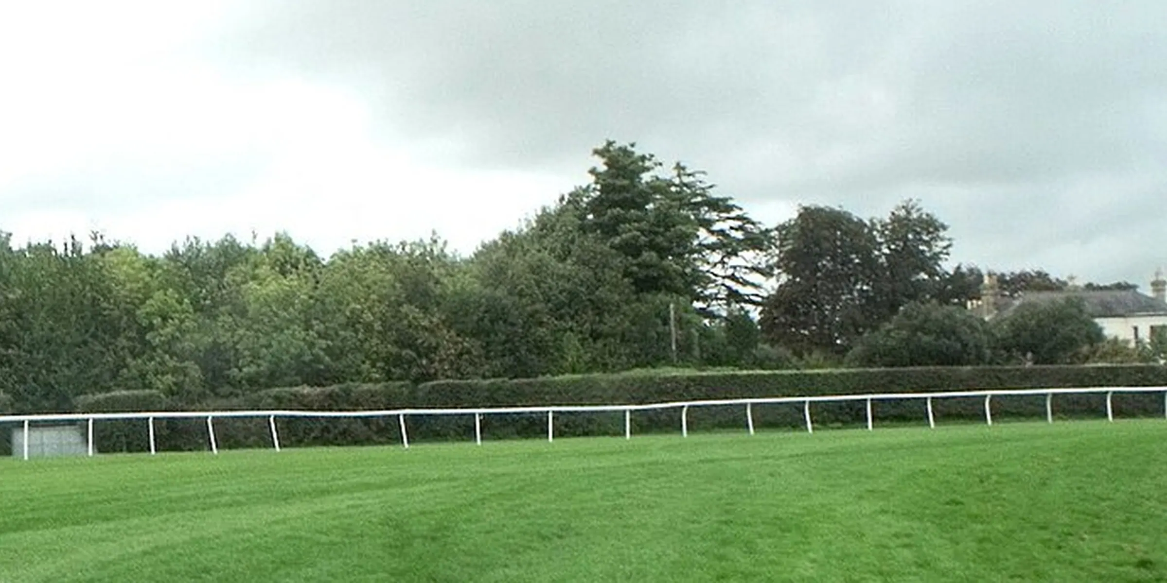 A quiet section of Fontwell with green turf, white rails and trees