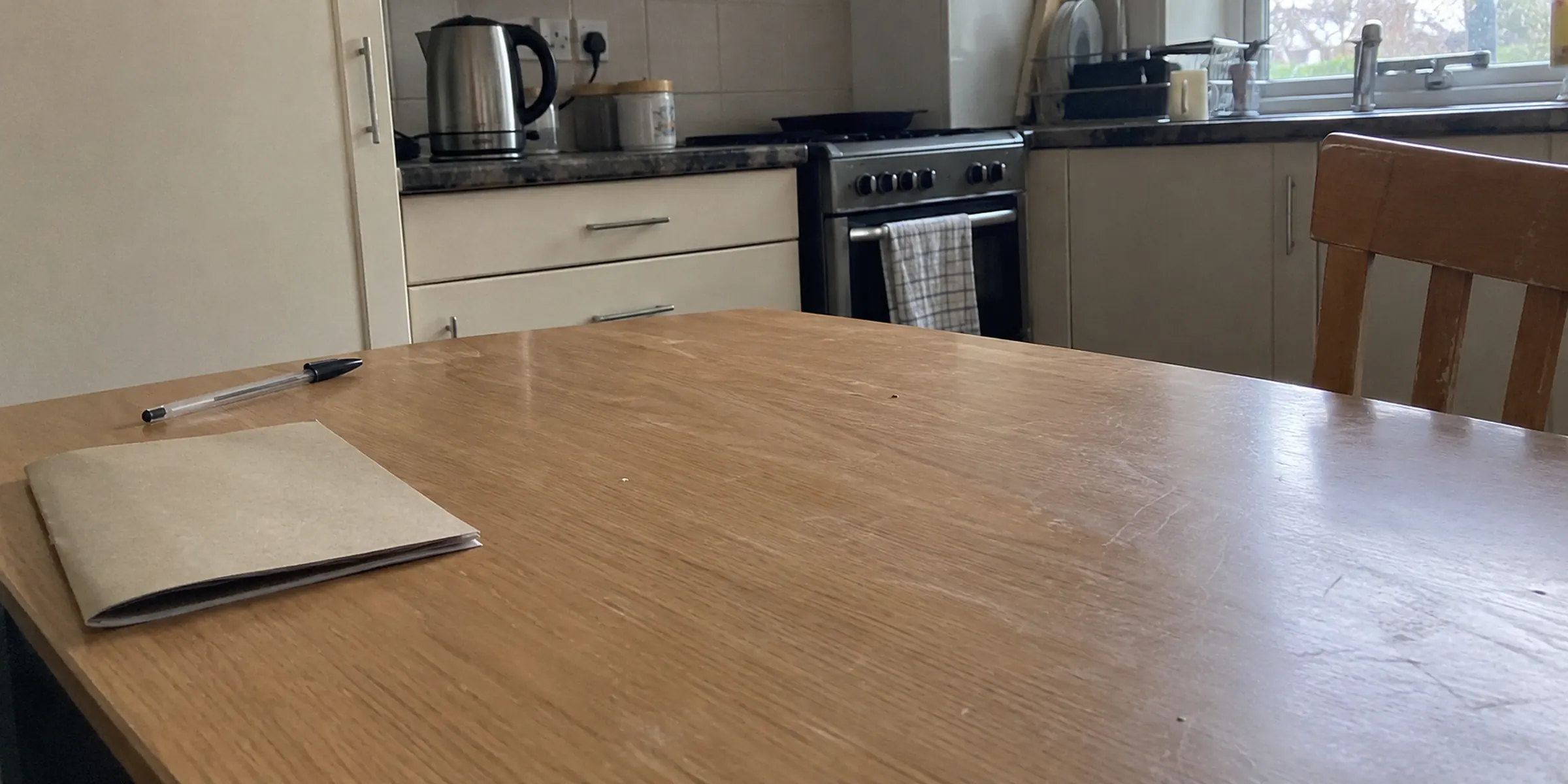 A closed buff programme and pen on a nearly empty kitchen table