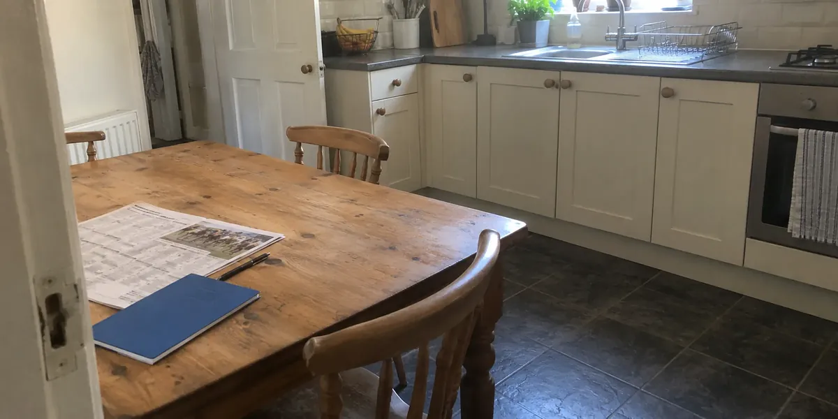A form sheet, blue notebook and pen left at one end of a kitchen table
