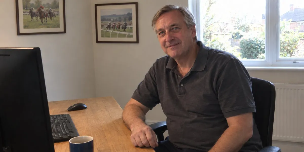 Lee at his desk at home, with two framed racing prints on the wall