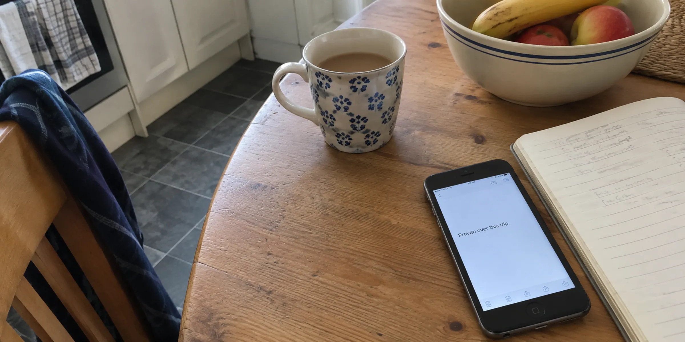 A phone displaying a single short sentence beside an open notebook
